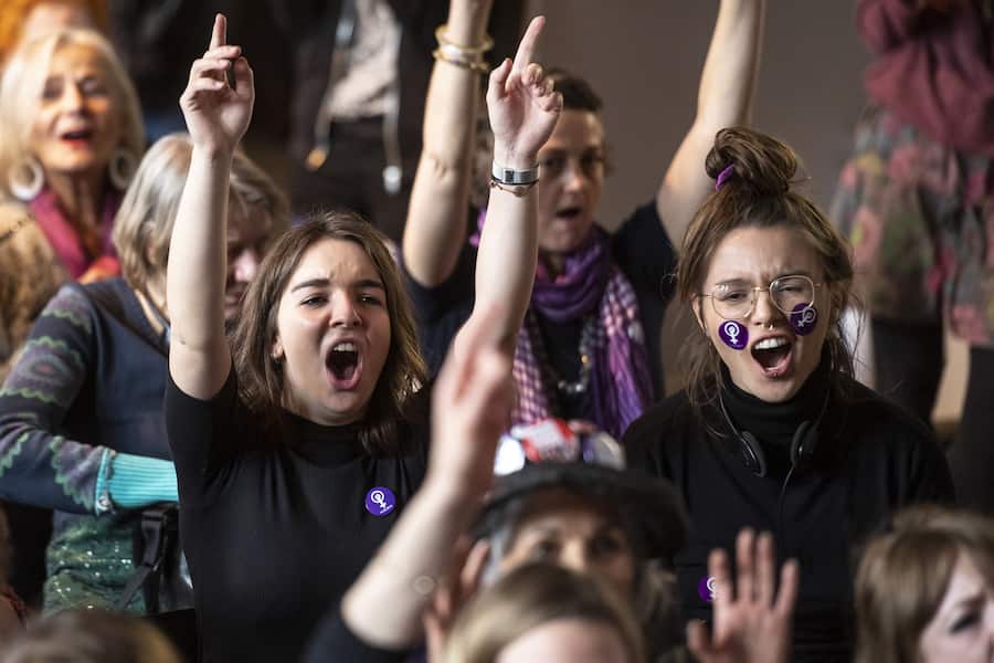 Des femmes font le signe du feminisme avec les mains, et brandissent des pancartes, lors d'une action collective organisee durant les Assises nationales pour la greve feministes et des femmes, ce dimanche 10 mars 2019 a la Maison du Peuple, a Bienne. (KEYSTONE/Adrien Perritaz)